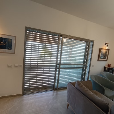 תריסים אפורים על חלון זכוכית בסלון מואר