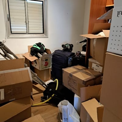 חדר עם קופסאות קרטון, מזוודה וציוד לאריזה