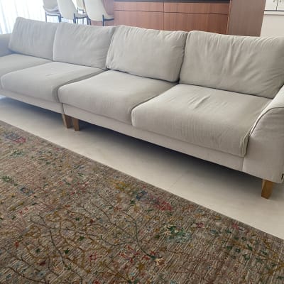 ספה בהירה על שטיח צבעוני בסלון מואר