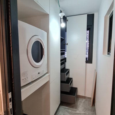 מכונת כביסה בחדר עם ארונות ומדרגות