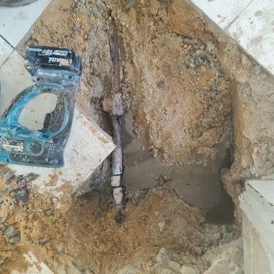 כלי עבודה ליד צינור שבור בחפירה באדמה