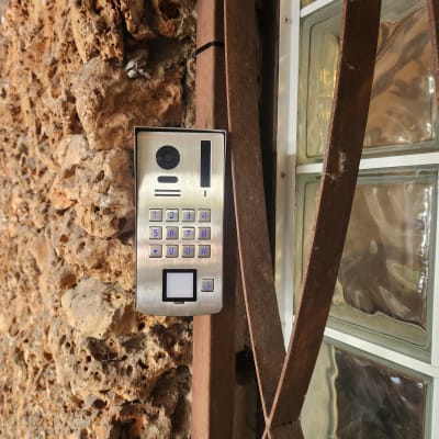 מערכת אינטרקום מותקנת על קיר אבן ליד חלון זכוכית