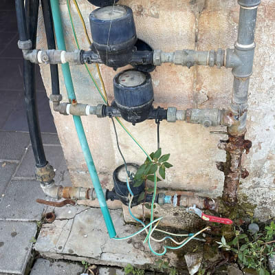 מד מים וצינורות מחוברים לקיר עם ברזים