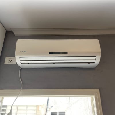 מזגן קיר לבן מותקן על קיר אפור