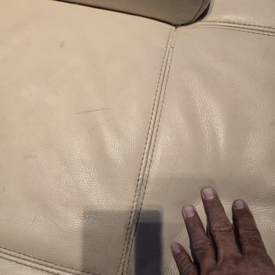 יד נוגעת בריפוד עור בהיר עם תפרים.