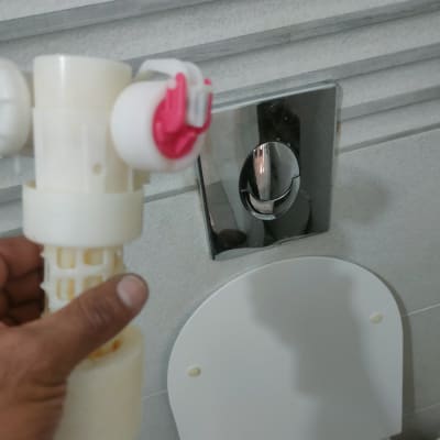 יד מחזיקה חלק פלסטיק ליד אסלה וכפתור הדחה