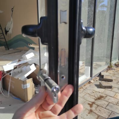 מנעול מותקן על דלת זכוכית עם ידית שחורה