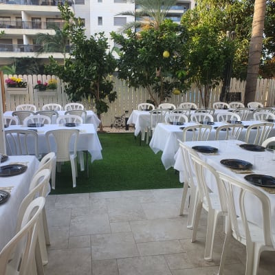 שולחנות ערוכים עם מפות לבנות וצלחות שחורות