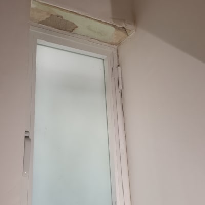 חלון עם קיר מתקלף מעליו, זקוק לתיקון