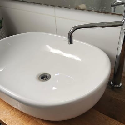 כיור לבן עם ברז כרום על משטח עץ