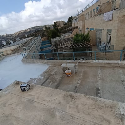 גג בניין עם חומרי איטום ודלי צבע