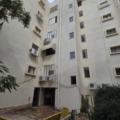 בניין מגורים עם מזגנים וספסלים בחצר