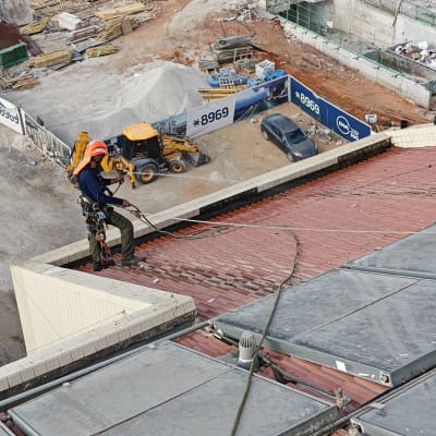 עובד על גג עם ציוד בטיחות באתר בנייה