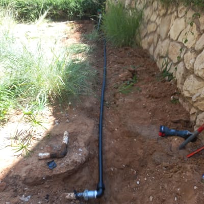 צינור שחור מונח באדמה עם מחברים וכלים