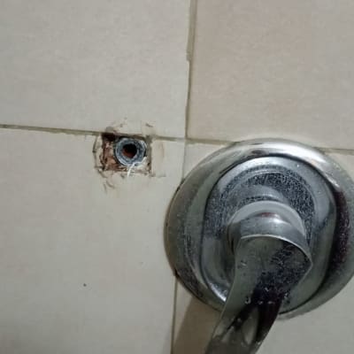 ברז מתכת על קיר אריחים עם חור חשוף