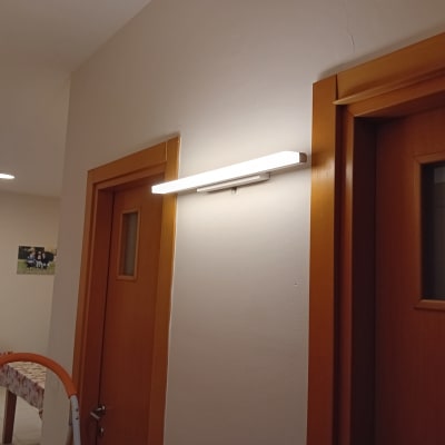 מנורת קיר דולקת ליד דלת עץ