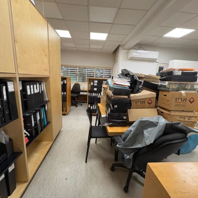 חדר עם ארגזים ומדפים מלאים בתיקיות ומסמכים