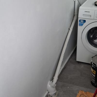 קיר צבוע ליד מכונת כביסה עם צינור ודלי צבע