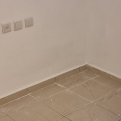 רצפה עם אריחים שרוטים ליד קיר עם שקעים