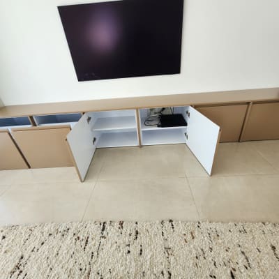 ארון פתוח עם דלתות לבנות מתחת לטלוויזיה תלויה