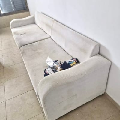 ספה לבנה עם חפצים על הרצפה ליד