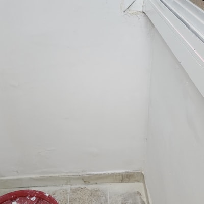 דלי צבע אדום על רצפה ליד קיר צבוע