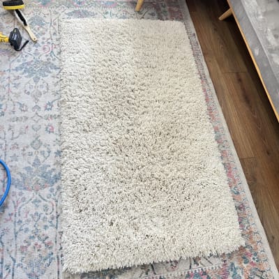 שטיח לבן על שטיח צבעוני עם מברשת וכלי ניקוי