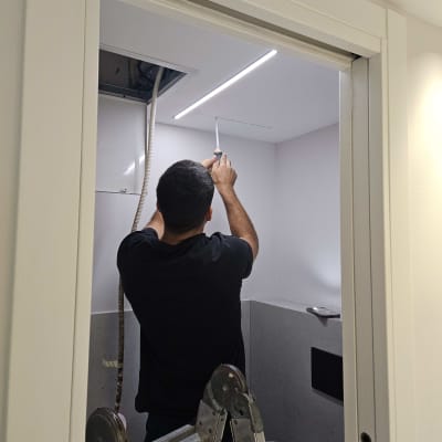 טכנאי מיזוג אוויר עובד בתקרת גבס ליד יחידה נסתרת