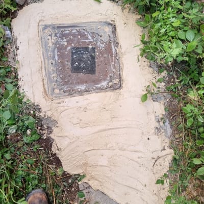 מכסה ביוב מרובע עם בטון מסביבו