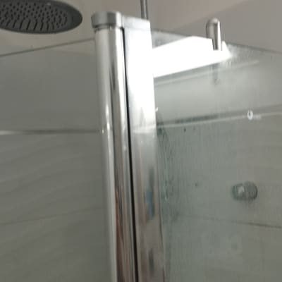 ראש מקלחת ודלת זכוכית במקלחת מודרנית