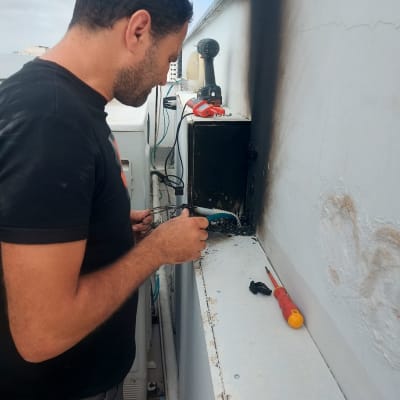 חשמלאי עובד על לוח חשמל עם מברג וכלים