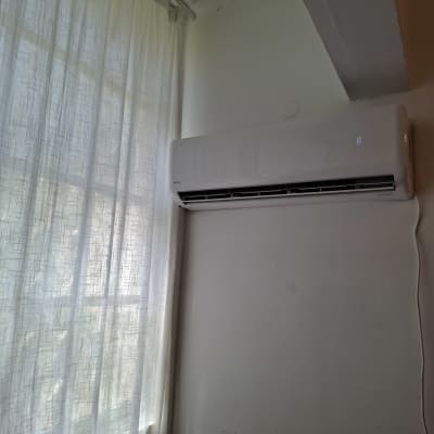 מזגן מותקן על קיר ליד חלון עם וילון