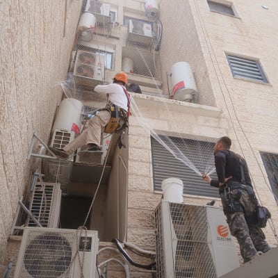 עובדים מתקינים רשת על בניין למניעת כניסת יונים