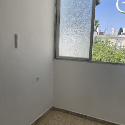 קיר צבוע בלבן ליד חלון עם מסגרת אפורה