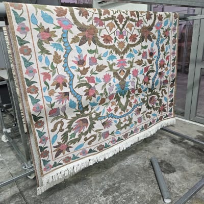 שטיח צבעוני תלוי לייבוש על מתקן מתכת