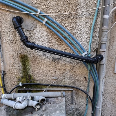 צינורות פלסטיק על קיר חיצוני עם צמחייה