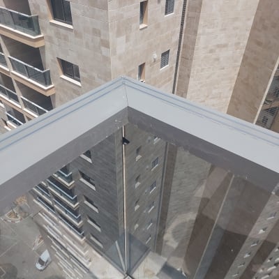 מעקה זכוכית עם פסי מתכת על מרפסת בניין