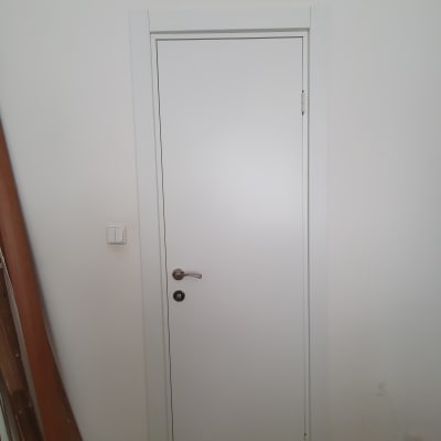 דלת לבנה עם ידית מתכת ומתג חשמל