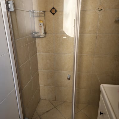 מקלחון עם בקבוק שמפו על מדף מתכת