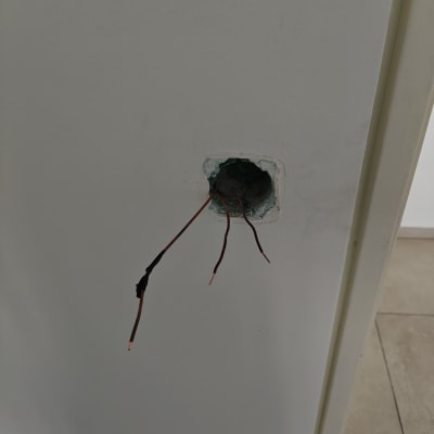 חוטי חשמל יוצאים מקיר עם חור עגול