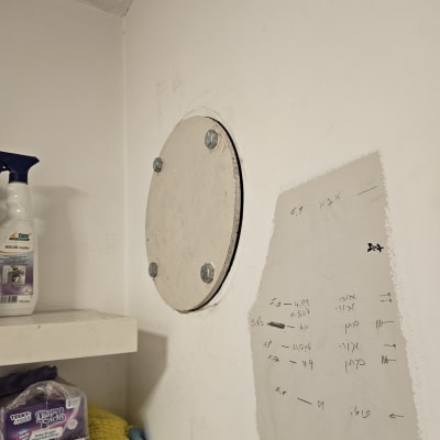 מדף עם מוצרי ניקוי וקיר עם לוח עגול מחובר