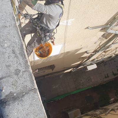 אדם עם קסדה עובד בגובה על קיר בניין