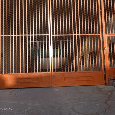 שער מתכת צבוע בצבע כתום עם דלת קטנה בצד