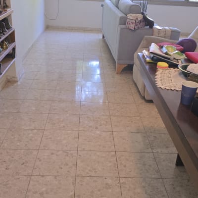 חדר מגורים עם רצפה נקייה ושולחן עמוס חפצים