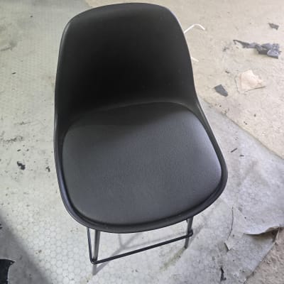 כיסא מרופד שחור על רצפה עם שאריות חומרים