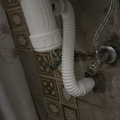 צינור ניקוז לבן מתחת לכיור עם ברזים