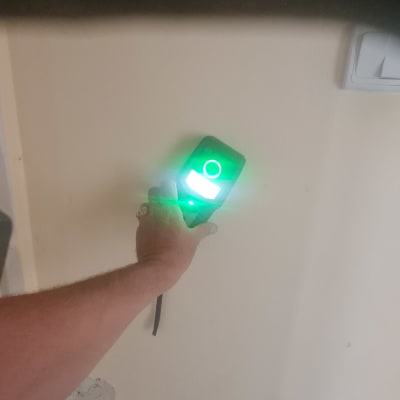 יד מחזיקה מכשיר מדידה על קיר עם טיח חשוף