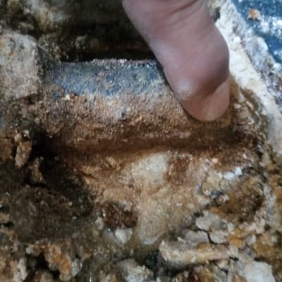 אצבע מצביעה על צינור חלוד עם נזילה