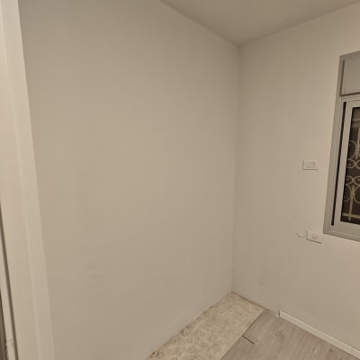 חדר עם קיר לבן ורצפת פרקט חלקית