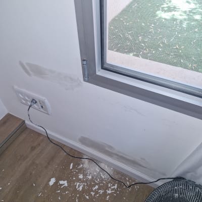 קיר עם תיקוני טיח וכתמי צבע, רצפה עם שאריות צבע